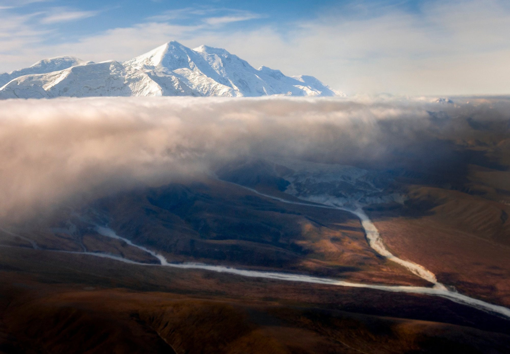 Low clouds spilling over braided river valleys beneath Denali in Denali National Park, Alaska