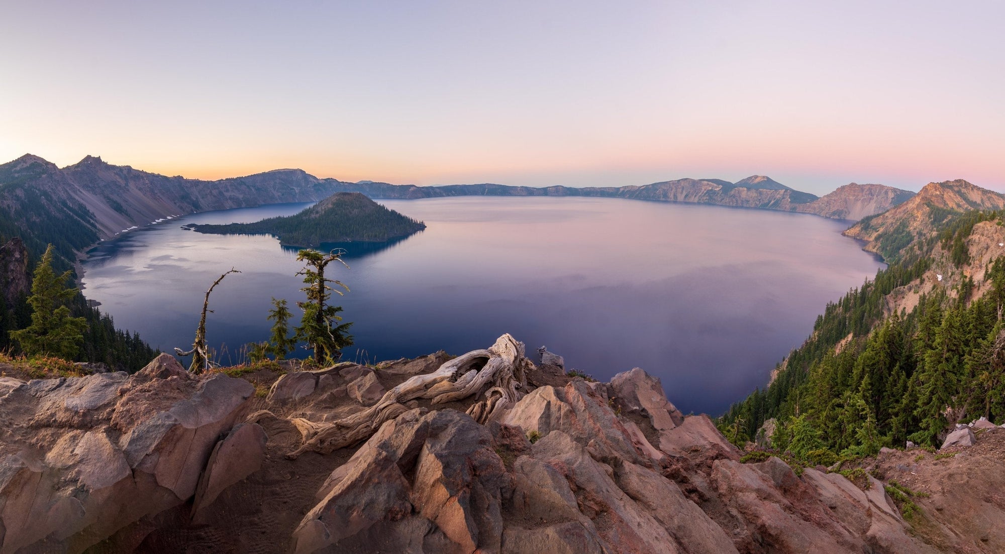 Crater Lake and Wizard Island at sunset viewed from rocky rim in Crater Lake National Park, Oregon