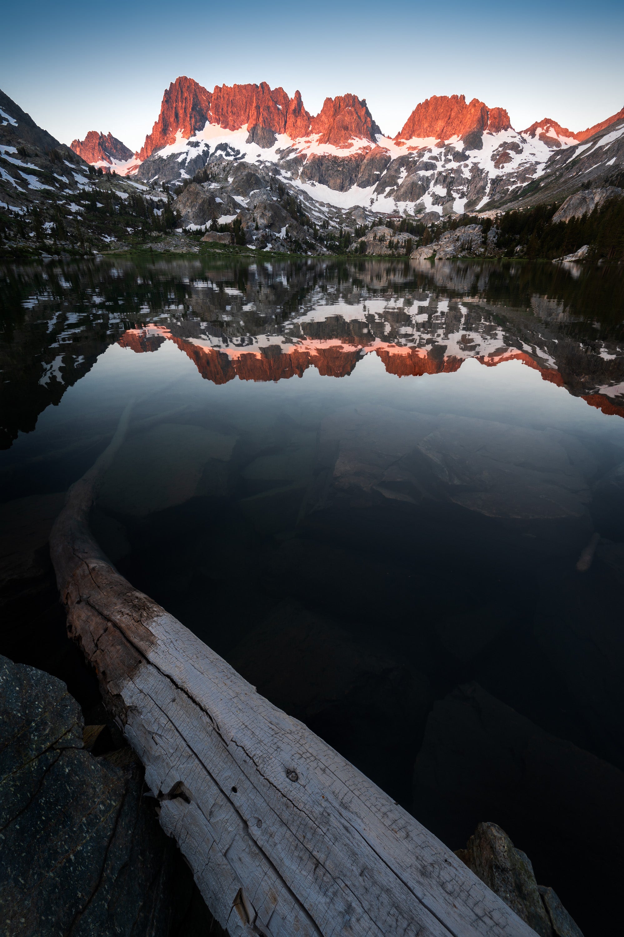 Sunrise at Ediza Lake in California’s Eastern Sierra, with the Minarets reflected in still, icy water beneath a clear early morning sky.